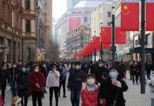 Beijing’s Growth Stalls — Hidden Rot Exposed Crowded street with people wearing masks and flags