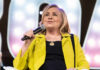 Person speaking into microphone wearing yellow jacket
