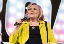 Person speaking into microphone wearing yellow jacket