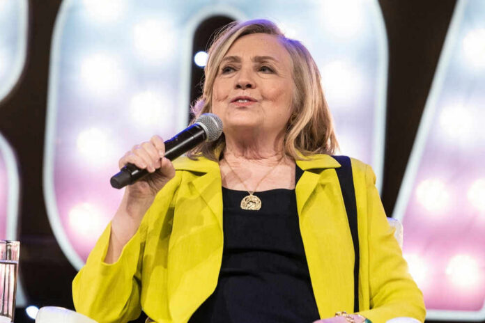 hillaryclintonid2176623881 Person speaking into microphone wearing yellow jacket