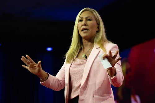 marjorie-taylor-greene-mtg2270821389jpg Woman speaking on stage wearing pink blazer