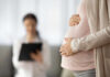 Older Moms Overtake Teens — Historic Shift Pregnant person holding their belly during a medical visit