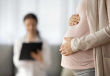 Older Moms Overtake Teens — Historic Shift Pregnant person holding their belly during a medical visit