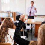 Hidden Delaware LLC Sparks Hill Firestorm Classroom with student raising hand teacher speaking front