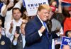MAGA Wave Crushes Party Rebels man in suit raising fists at a rally podium