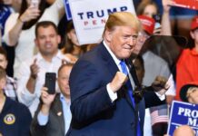 MAGA Wave Crushes Party Rebels man in suit raising fists at a rally podium