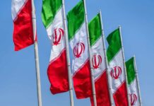 Strikes Near Hospital? Proof Or Propaganda? Multiple Iranian flags waving against a clear blue sky