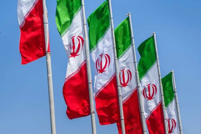 Group,Of,Iran,Flags,Against,Blue,Sunny,Sky,Background Multiple Iranian flags waving against a clear blue sky