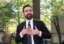Socialist Shock: Wall Street Blinks? Man in suit speaking with hands on chest outdoors
