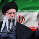 Iran Power Vacuum Whispers Grow Iranian flag waving above a government building against a blue sky