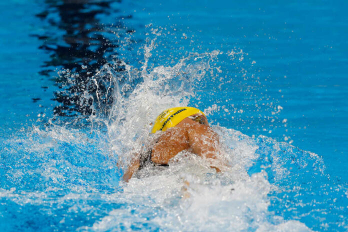 Swimmer in yellow cap racing in pool