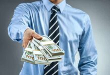 Winning Ticket Ruse Drains $5K Fast Person in business attire offering bundles of US dollar bills
