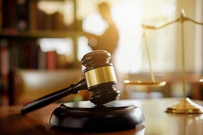 shutterstock_1081695923 Judge's gavel on a desk with scales of justice in background