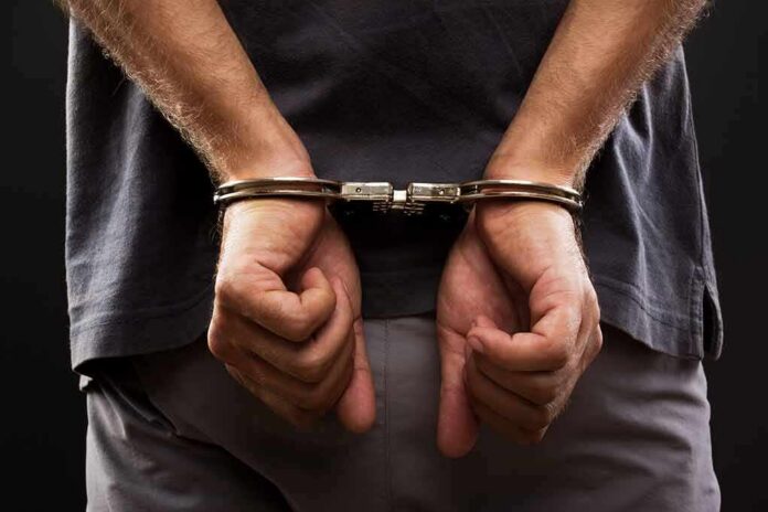 person with hands cuffed behind back