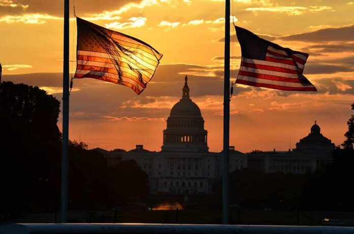 shutterstock_113389501 U.S. Capitol silhouette with American flags at sunset