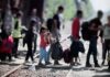Inside The $150M Switch Rocking Immigration Courts People with bags walking along railway tracks