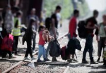 Inside The $150M Switch Rocking Immigration Courts People with bags walking along railway tracks