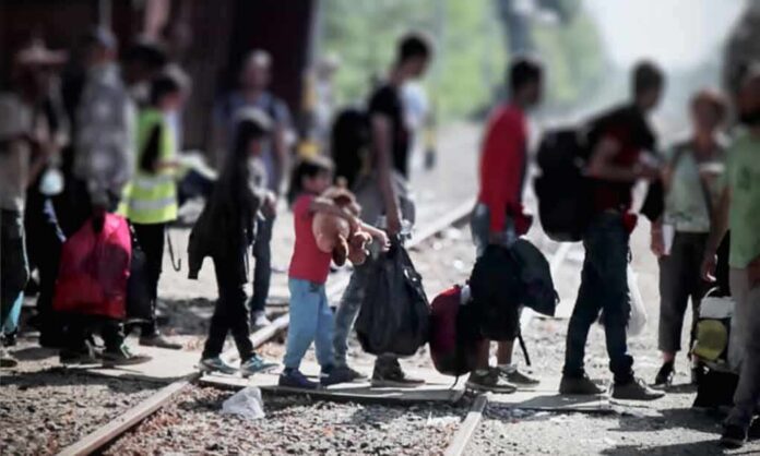People with bags walking along railway tracks