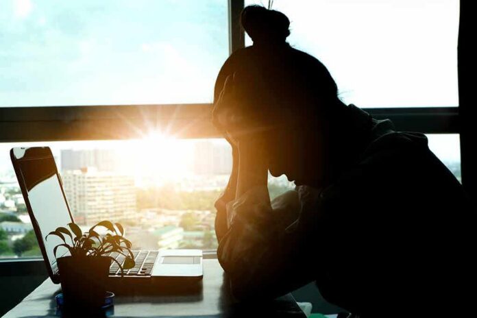 shutterstock_1223165929 silhouetted person at a desk with head in hands