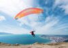 Paraglider launching over a coastal city and blue sea