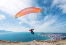 Paraglider Smash Sparks Daring Cliff Hoist Paraglider launching over a coastal city and blue sea