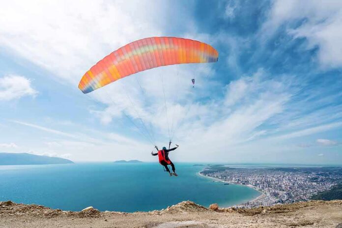 shutterstock_2153077121 Paraglider launching over a coastal city and blue sea