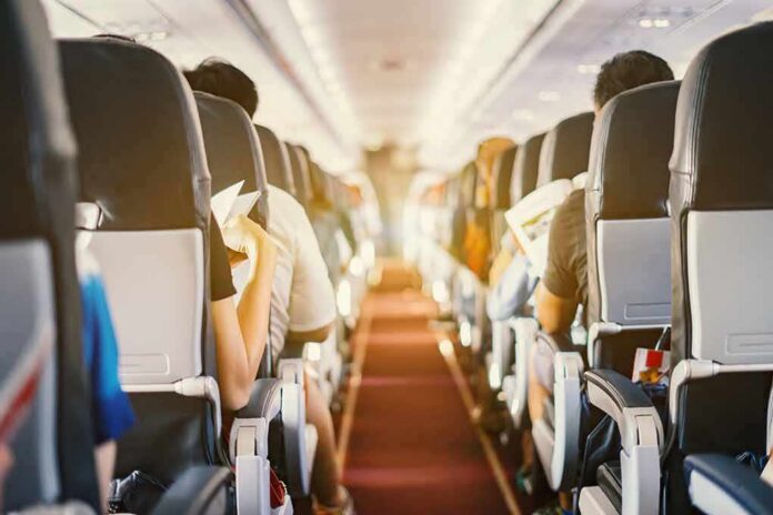 shutterstock_626651186 Airplane cabin aisle with passengers seated