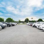 Parking lot lined with cars under a blue sky