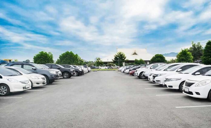 shutterstock_797260003 Parking lot lined with cars under a blue sky