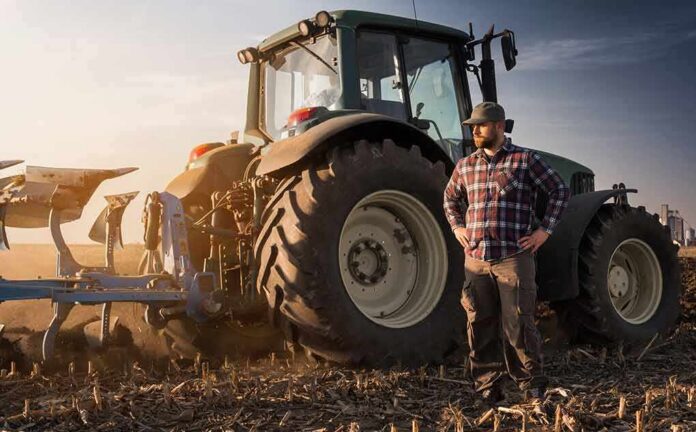 Farmer standing beside a tractor in a plowed field