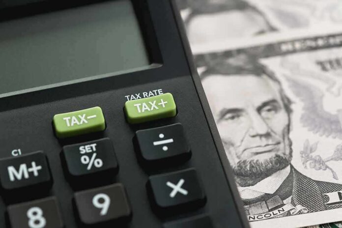 shutterstock_1040591914 Calculator with tax buttons beside U.S. currency