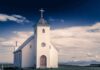 Pulpit Blast Ignites Tribal Showdown White countryside church with steeple and cross under a dramatic sky
