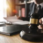 Lavish Life on Fake Truck Cash – Grand Jury Hits Alleged Fraud King Judge's gavel on desk with person reading documents in background