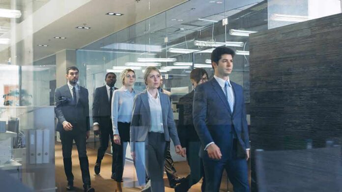 shutterstock_1120845563 Business team walking through modern glass-walled office