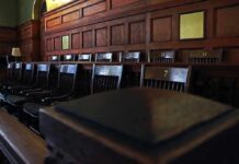 Holdout Hunted – Jury Independence At Risk Empty wooden jury box with numbered chairs