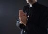 Chicago Priest Back — Transparency Still Missing Clergyman in black robe praying with hands together