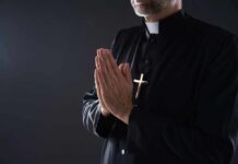 Clergyman in black robe praying with hands together