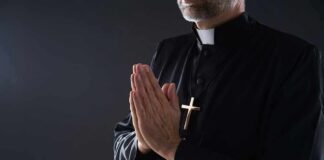 Clergyman in black robe praying with hands together