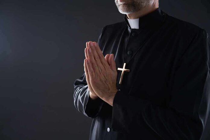 Clergyman in black robe praying with hands together
