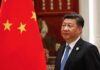 Red-Carpet Trap For Xi? Tarmac Power Move Ups The Stakes Xi Jinping standing beside a Chinese flag