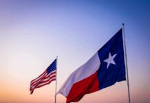Texas and United States flags waving at sunset
