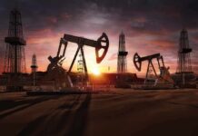 Oil pumpjacks and derricks at sunset in a desert field