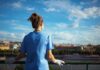 Healthcare worker in blue scrubs overlooking a cityscape