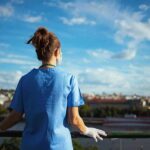 Healthcare worker in blue scrubs overlooking a cityscape