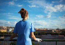 Operation Nightingale Unmasks Hospital Fraud Healthcare worker in blue scrubs overlooking a cityscape