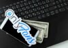 Substitute Booted – OnlyFans Uproar Halts Missouri Classrooms Smartphone with OnlyFans sticker and cash on a laptop keyboard