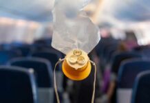 airplane oxygen mask hanging in cabin aisle