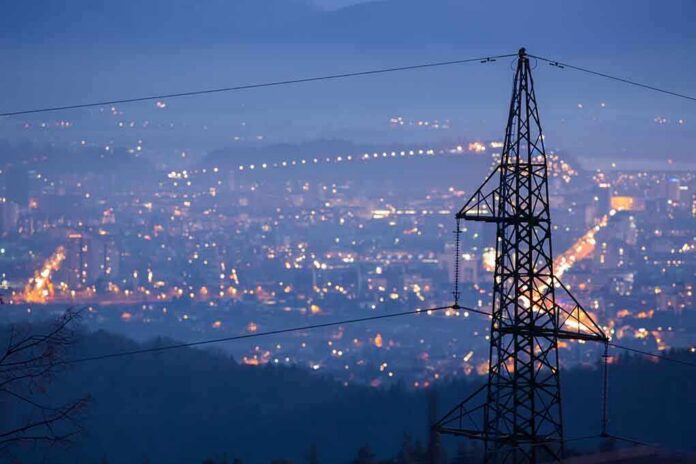 Night view of a city skyline with power lines in the foreground