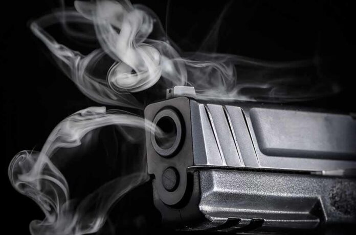 shutterstock_365659679 Close-up of a handgun muzzle with smoke swirling from the barrel