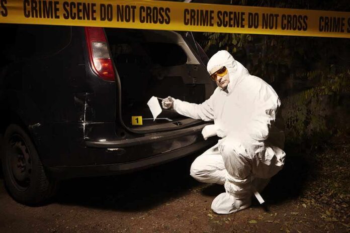 forensic investigator at car trunk behind crime scene tape